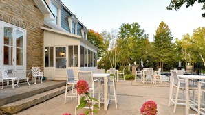 An outdoor patio with white furniture, a brick building, and a glass enclosure. - Nevis Estate Boutique Hotel (Perth)