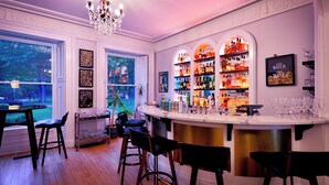 A bar area with a bar counter, stools, and shelves of liquor bottles. - Nevis Estate Boutique Hotel (Perth)