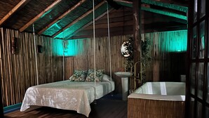 Een kamer met een bed, een hangstoel, een wastafel en een bad.