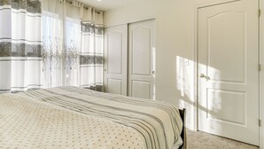 Une chambre à coucher avec un lit, des rideaux, une armoire et une porte.
