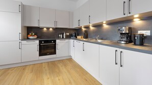A modern kitchen with white cabinets, a built-in oven, a coffee machine, and a sink. - Central | Modern | Old Town | Parking lot | 70 m² (Bad Kreuznach)