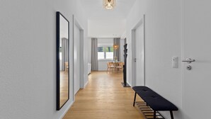 A hallway with a bench, a dining area with a table and chairs, and a large mirror on the left wall. - Central | Modern | Old Town | Parking lot | 70 m² (Bad Kreuznach)