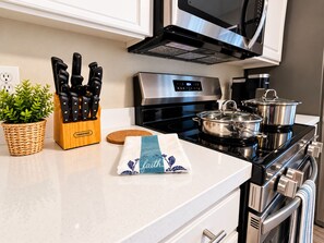 Una cocina con microondas, estufa y diversos utensilios de cocina.