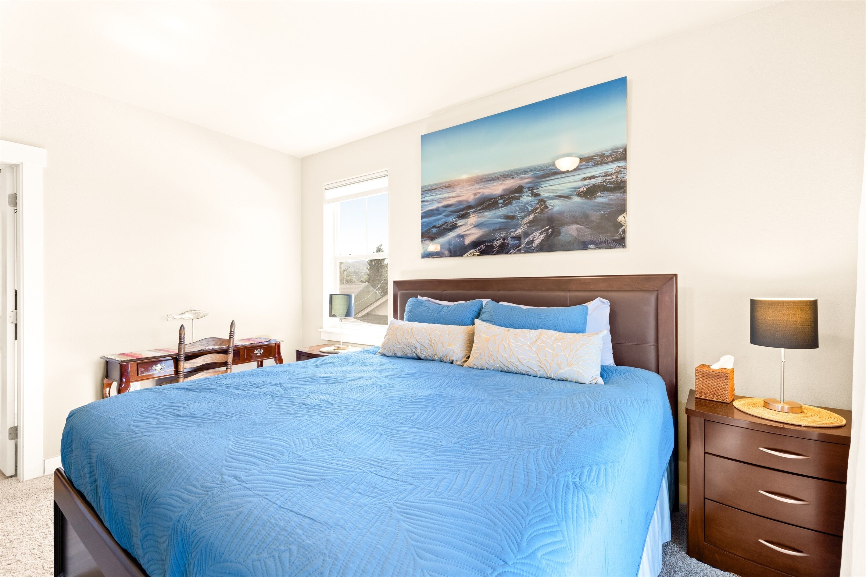 Une chambre à coucher avec un grand lit, une table de chevet, un bureau et un tableau au mur.
