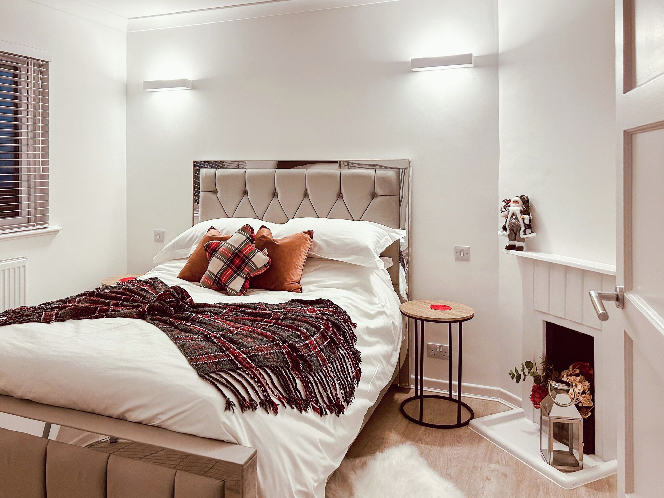Un dormitorio con cama, mesita de noche y una pequeña chimenea.