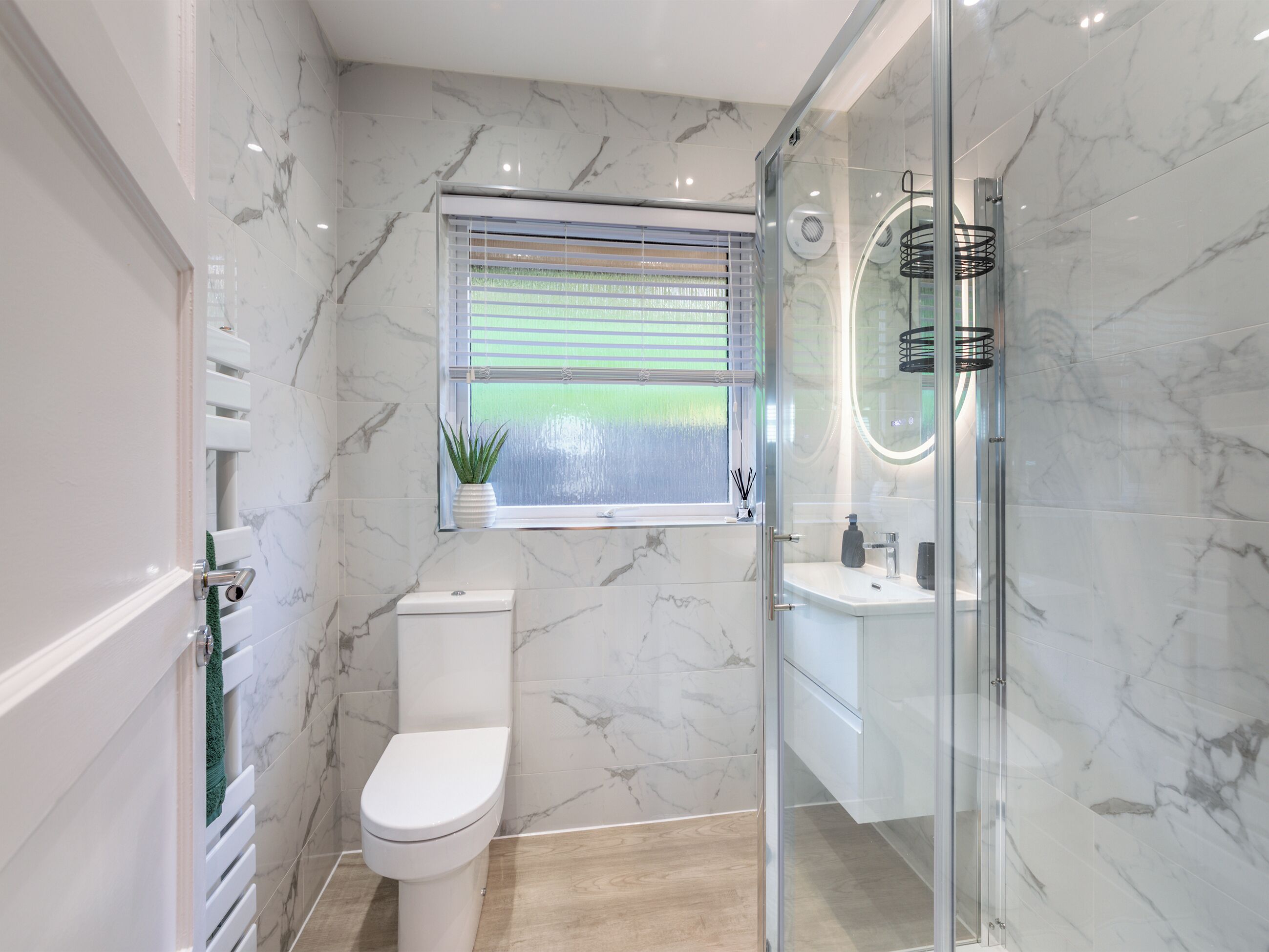 Un baño moderno con inodoro, una ventana con persianas, zona de ducha y lavamanos.