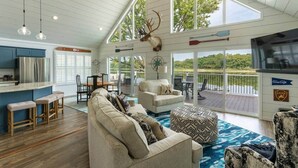 A spacious living area with a large window, a ceiling fan, and a mounted deer head. - Insta-worthy Rock River cabin (Byron)