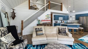 A spacious living area with a high ceiling, a staircase, a kitchen, and a dining area. - Insta-worthy Rock River cabin (Byron)
