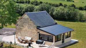 A stone house with a sloped roof and a patio area with outdoor furniture.