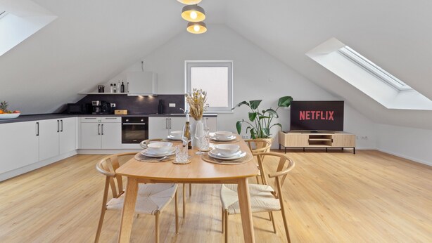 Moderni keittiö, jossa on ruokailutila, televisio, jolla näkyy Netflix, ja kattovalokuvio.