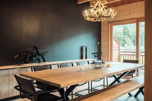 A wooden dining table with benches, a chandelier, and a view of the outdoors. - Le Chalet des Belles - Perfect for a family break (Praz-sur-Arly)