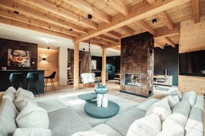 A modern living room with a large sectional sofa, a round coffee table, and a stone fireplace. - Le Chalet des Belles - Perfect for a family break (Praz-sur-Arly)