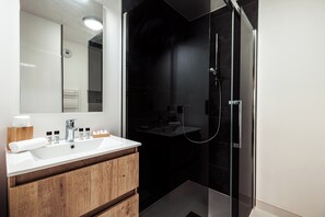 A modern bathroom with a white sink, wooden vanity, and a glass-enclosed shower area. - Apartment Nid des Neiges - Perfect for families (Combloux)
