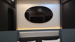 Et moderne hotelværelse med en stor seng, et rundt spejl og indbygget belysning.