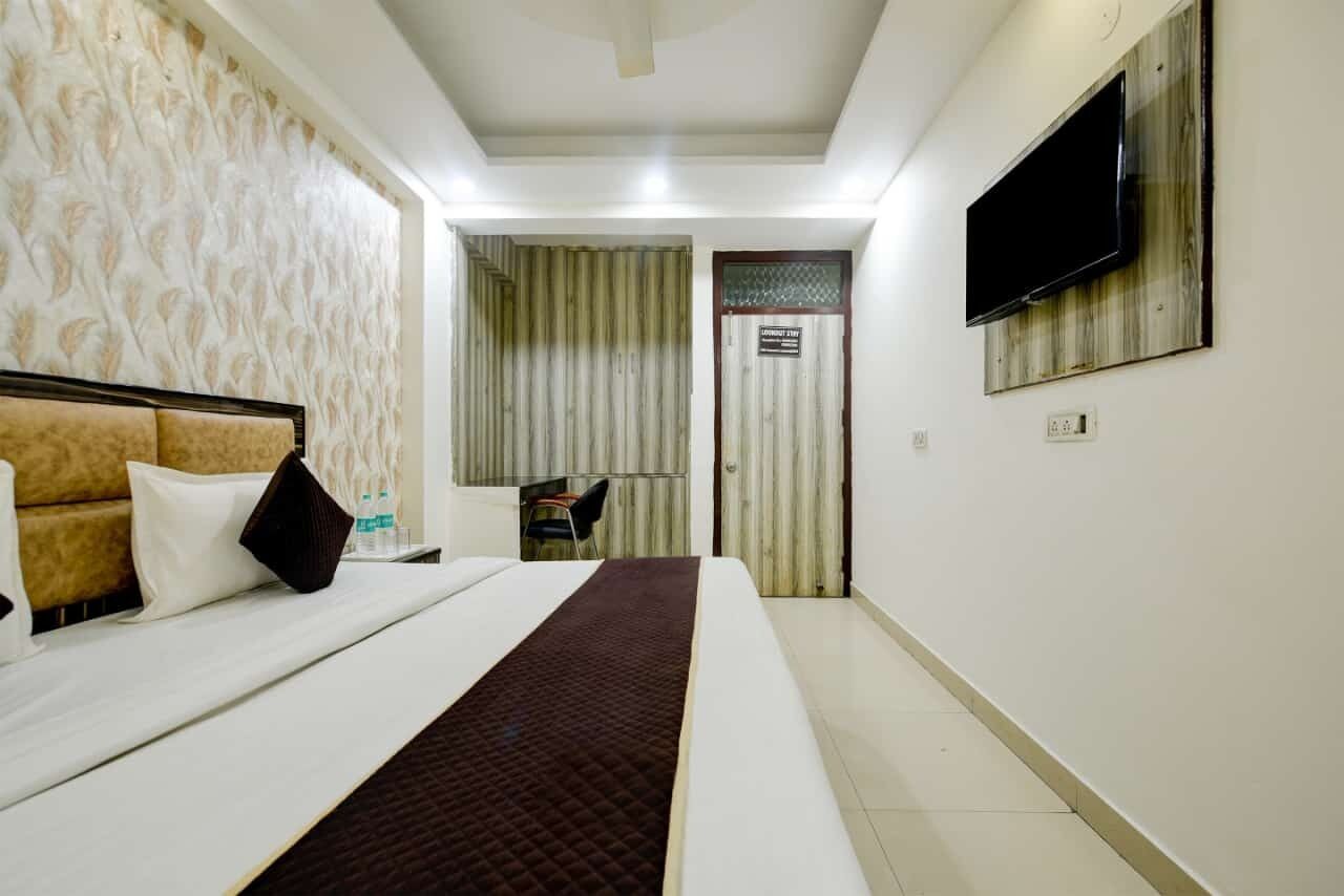 A hotel room with a bed, a TV mounted on the wall, and a door leading to a bathroom.