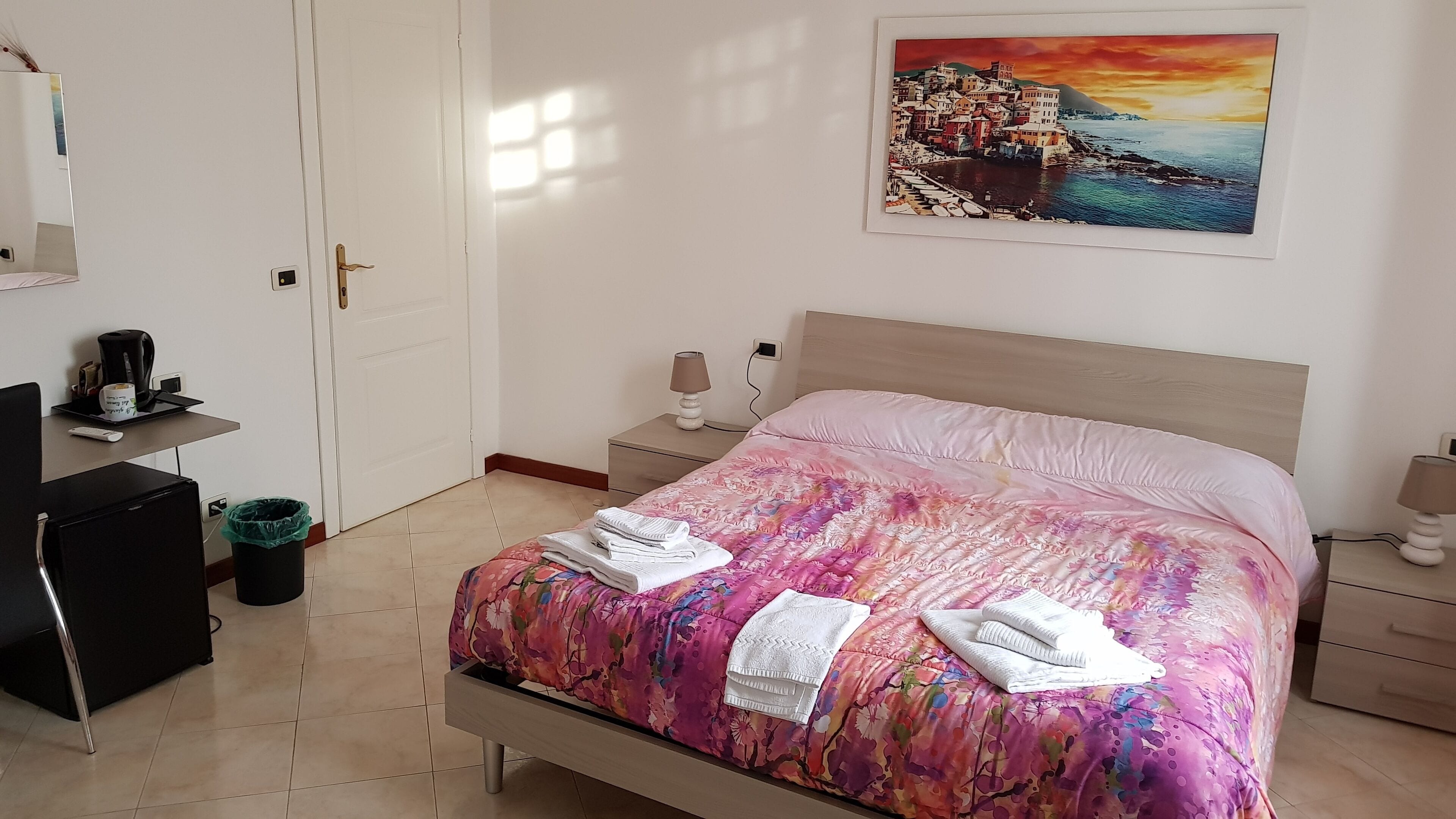 A neatly arranged bedroom with a bed, bedside tables, a desk, and a chair.