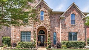 A two-story stone house with a central entrance, a brick chimney, and a well-maintained lawn. - Luxurious Retreat:Heated Pool, Hot Tub Media R, Minutes from Universal Kids Park (Frisco)