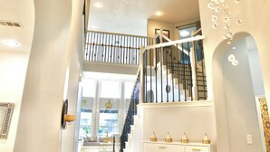 A modern interior with a staircase, a decorative wall, and a view of the outdoors. - Luxurious Retreat:Heated Pool, Hot Tub Media R, Minutes from Universal Kids Park (Frisco)