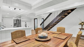 A modern kitchen with white cabinetry, a stainless steel refrigerator, and a built-in island with a sink.