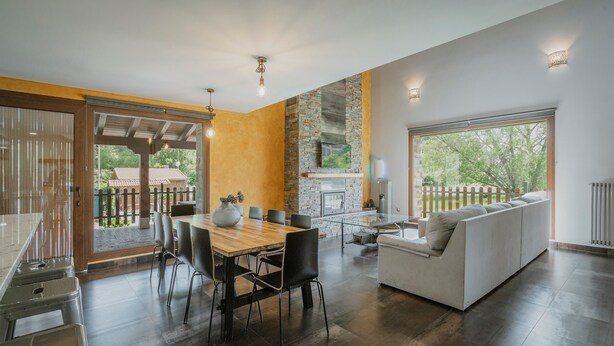 Un interior moderno con comedor, sofá y chimenea.