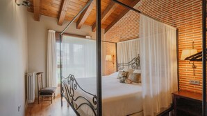 A four-poster canopy bed with a wooden headboard, a radiator, and a chair in a room with brick walls and wooden flooring. - Country House 'La Puerta Del Río Lobos I' with Private Pool, Shared Terrace and Wi-Fi (San Leonardo de Yagüe)