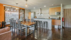 A modern kitchen with a dining area, wooden cabinets, and a stainless steel microwave. - Country House 'La Puerta Del Río Lobos I' with Private Pool, Shared Terrace and Wi-Fi (San Leonardo de Yagüe)