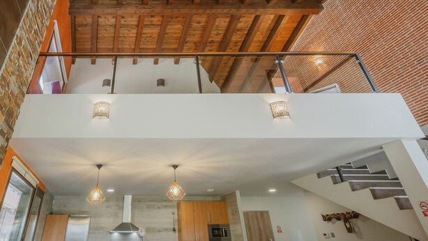 A modern interior with exposed wooden beams, a mezzanine level, and a kitchen area. - Country House 'La Puerta Del Río Lobos I' with Private Pool, Shared Terrace and Wi-Fi (San Leonardo de Yagüe)