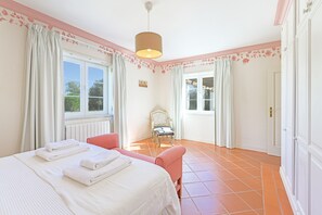 A bedroom with a bed, a chair, a window, and a door.
