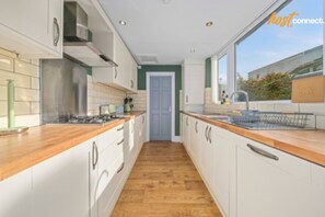 A modern kitchen with white cabinets, wooden countertops, and a central island.