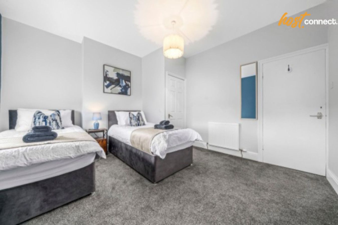 Une chambre moderne avec deux lits, une grande fenêtre et une porte blanche.