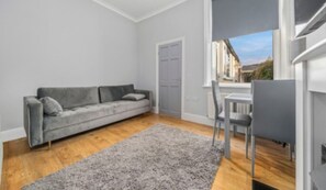 A modern living room with a grey sofa, a small table, and a grey rug.