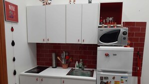 A compact kitchen with white cabinets, a microwave, a refrigerator, and a sink. - CYRIL 31 IN THE HISTORIC CENTER (Napoli)