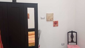 A bedroom with a wardrobe, a chair, and two wall-mounted artworks. - CYRIL 31 IN THE HISTORIC CENTER (Napoli)