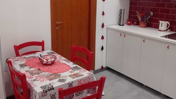 A small kitchen with a dining table and chairs, a wooden door, and a kitchen counter with cabinets. - CYRIL 31 IN THE HISTORIC CENTER (Napoli)