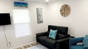 A living room with a black sofa, a blue sofa, a blue rug, a clock, and a TV. - Tequila Time in Rockport, TX (Rockport)