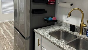 A modern kitchen with a stainless steel refrigerator, granite countertop, and a gold faucet. - Tequila Time in Rockport, TX (Rockport)