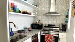 A compact kitchen with white cabinets, stainless steel appliances, and a patterned backsplash. - Tequila Time in Rockport, TX (Rockport)