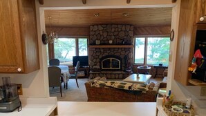 A kitchen with a stone fireplace, wooden cabinets, and a view of the outdoors. - Lakefront Octagon!! 3 Master Suites. Fiber Optic Internet, 1Gb down/IGb Up (Three Lakes)