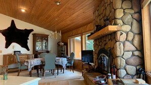 A cozy living room with a stone fireplace, wooden ceiling, and a large animal hide on the wall. - Lakefront Octagon!! 3 Master Suites. Fiber Optic Internet, 1Gb down/IGb Up (Three Lakes)