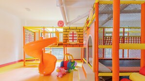 A play area with a slide, soft play structures, and a netted climbing wall. - Riverside Retreat - Nairobi Apartment (Nairobi)