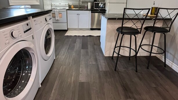 Una cocina compacta con electrodomésticos integrados, lavadora y comedor con taburetes de bar.