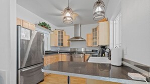 Una cocina moderna con electrodomésticos de acero inoxidable, armarios de madera y encimera de granito.