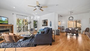 Amplia sala de estar con chimenea, una mesa de comedor con sillas y una zona de cocina con mesa y sillas.