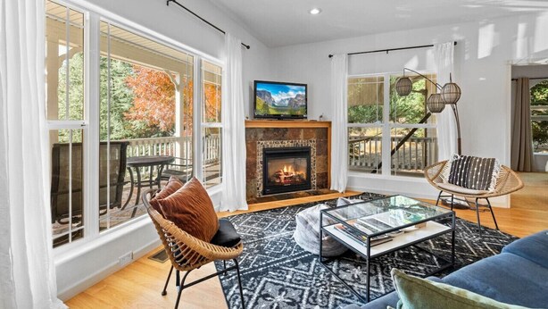 Una sala de estar amplia con chimenea, ventanas grandes y un balcón.