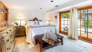 A bedroom with a bed, bedside tables, a bench, a dresser, and a view of the outdoors through large windows. - Las Olas Oasis by Avantstay Minutes to the Beach + Hot Tub (Fort Lauderdale)