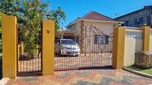 A gated entrance with a numbered gate, a parked car, and a building with a tiled roof. - Charming Seaview Studio with Private Pool & Complimentary Airport Transfer! (Hopewell)