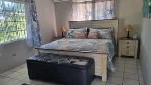 A bedroom with a bed, bedside tables, a bench, a window with curtains, and an air conditioning unit. - Charming Seaview Studio with Private Pool & Complimentary Airport Transfer! (Hopewell)