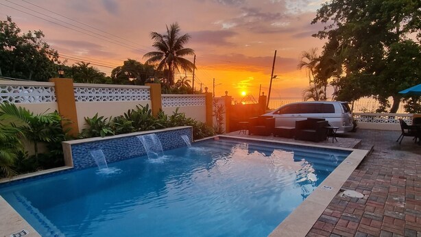 A swimming pool with a waterfall feature, surrounded by a brick patio and a white fence. - Charming Seaview Studio with Private Pool & Complimentary Airport Transfer! (Hopewell)