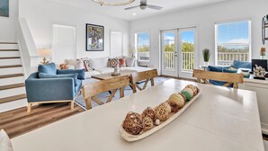 A spacious living room with a wooden dining table, blue sofas, and a chandelier.