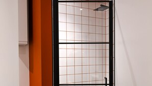 Een moderne badkamer met een douchecabine van glas, een zichtbare afvoer en een betegelde vloer.